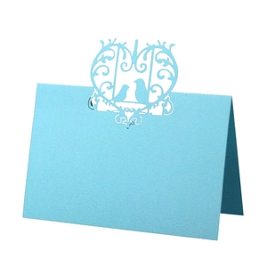 Detail of light blue laser cut wedding place card with intricate bird and heart motif