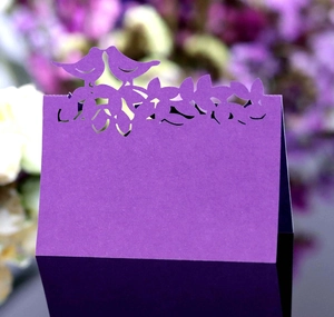 Détail d'un marque-place violet découpé au laser avec oiseaux sur une branche
