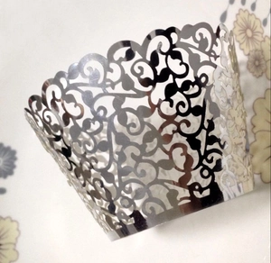 Macro detail of laser-cut silver vine pattern on elegant cupcake wrappers for desserts