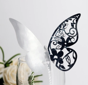 Detailed laser-cut hollow butterfly place card on a glass rim for wedding table decor