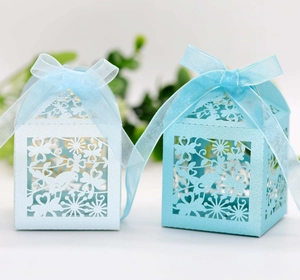 Detail of laser-cut wedding candy boxes with birds and floral patterns in blue tones
