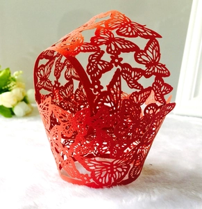Intricate laser-cut red paper cupcake wrappers featuring delicate butterfly patterns