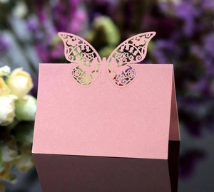 Macro shot of pink laser-cut butterfly place card with delicate hollow design for weddings