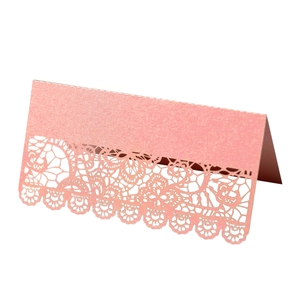 Detail of pink pearlescent table card with laser-cut lace floral pattern and folding design