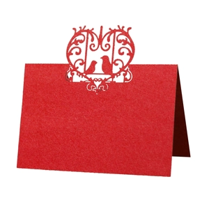 Red laser-cut table place card with bird design and floral hollow patterns for weddings