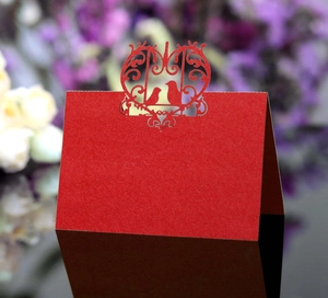 Detail of red laser-cut place card with bird motifs on textured matte cardstock