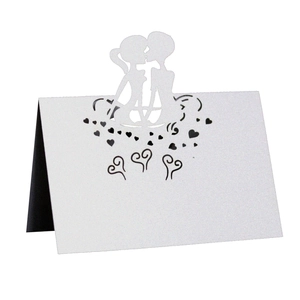Detail of laser-cut wedding place card featuring a white romantic couple silhouette