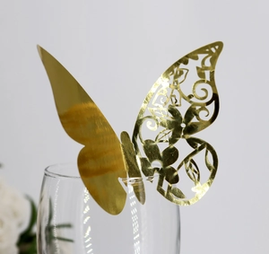 Golden 3D laser-cut butterfly place card for wedding table decoration on a glass