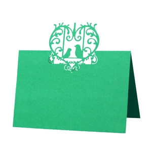 Macro detail of laser-cut green place card featuring heart and bird wedding motifs