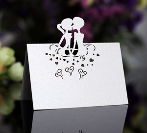 Macro detail of laser-cut wedding place card with kissing couple silhouette and heart