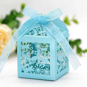 Detail of laser-cut wedding candy box with bird and heart patterns and blue ribbon