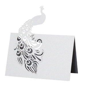 Detailed laser-cut peacock wedding place card in pearlescent white paper showing texture