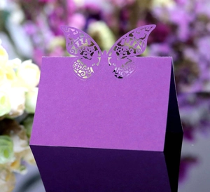 Macro shot of laser-cut butterfly detail on a deep purple wedding place card