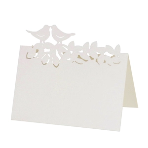 Détail de marque-place découpé au laser blanc nacré avec motifs oiseaux et arbre de vie