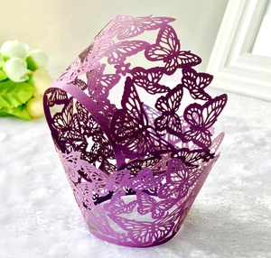 Macro shot of purple laser-cut butterfly cupcake wrappers on white plush background