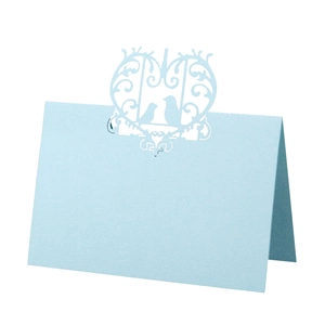 Detail of light blue laser-cut wedding place card featuring heart and bird patterns