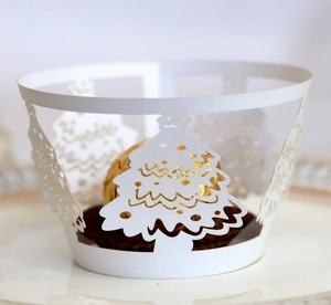 Laser-cut white cupcake wrapper with gold Christmas tree patterns and elegant hollow design
