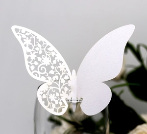 Detail of laser-cut white butterfly glass card with floral pattern for wedding decor