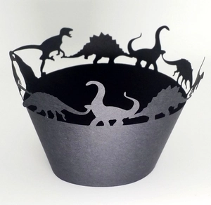 Macro detail of laser-cut dinosaur silhouette cupcake wrappers in black matte paper