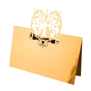 Macro detail of laser cut gold place card featuring intricate bird and floral patterns
