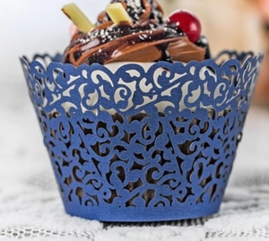 Macro detail of laser-cut dark blue pearlescent paper cupcake wrapper with vine pattern