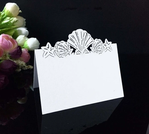 Détail du marque-place de mariage blanc découpé au laser avec coquillages et étoiles de mer