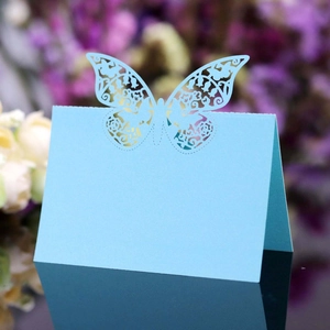 Macro shot of laser-cut butterfly place card with intricate floral patterns for weddings