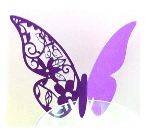 Macro shot of purple laser-cut paper butterfly with floral hollow patterns and solid wing