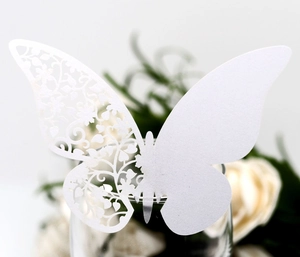 Detailed laser-cut white butterfly paper place card set on a glass for wedding decor