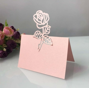 Vue détaillée du marque-place rose nacré avec motifs de roses et feuilles découpés au laser