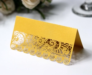 Detailed laser-cut floral pattern on a golden pearlescent wedding place card
