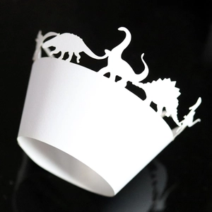 Close-up of laser-cut white cardstock cupcake wrapper featuring dinosaur silhouettes