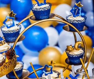 Three-tier golden metal cake stand with laser-cut blue cupcake wrappers and star toppers
