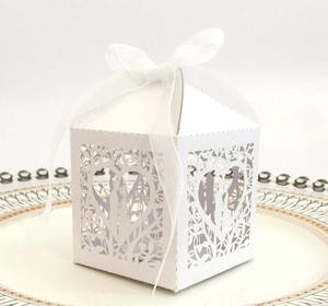 Elegant white laser-cut wedding favor box with heart patterns and organza ribbon