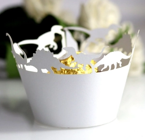Close-up of laser-cut white dinosaur cupcake wrappers with elegant hollow patterns