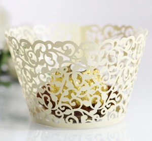 Detail of laser-cut vine patterns on cream cupcake wrappers for wedding desserts