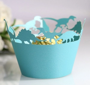 Close-up of laser-cut dinosaur cupcake wrapper in light teal with a golden chocolate