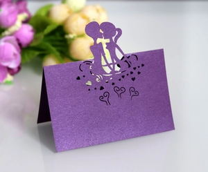Detail of laser-cut purple pearl paper wedding place card with couple silhouette