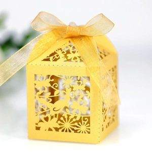 Detail of yellow laser-cut gift box featuring bird and floral patterns with gold ribbon