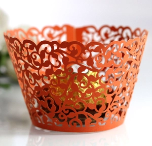 Macro shot of orange laser-cut cupcake wrappers with elegant vine and scroll patterns