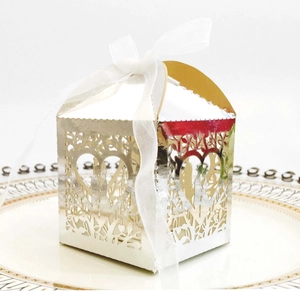 Close-up of laser-cut wedding favor box with intricate heart pattern and white ribbon