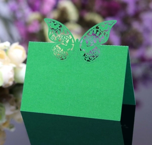 Detail of green laser-cut butterfly place card with intricate patterns on high-quality paper