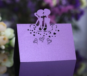 Detail of purple pearlescent place card with laser cut kissing couple and hearts