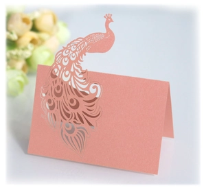 Detail of pink laser-cut peacock place card with shimmer finish for wedding tables