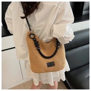 Detail of woven crossbody bag with black beaded handle and shoulder strap on model