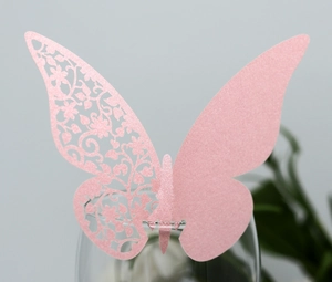 Detail of pink laser-cut butterfly cup card with glitter texture for wedding party