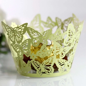 Macro view of laser-cut light green cupcake wrapper with intricate butterfly pattern