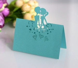 Close-up of laser-cut place card showing a kissing couple silhouette in light blue paper