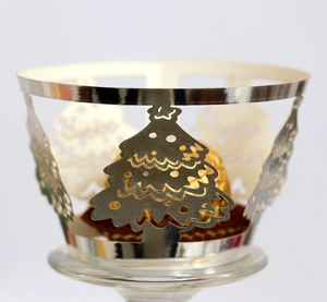 Macro view of silver laser-cut cupcake wrappers with Christmas tree patterns for decor