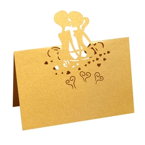 Macro view of gold laser-cut wedding place card with kissing couple silhouette and hearts